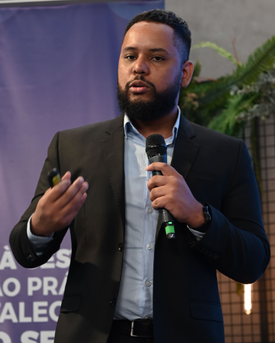 Foto de Hathos Gomes em um evento apresentando algo